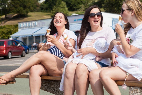 Three young women breastfeeding their babies whilst eating ice-creams