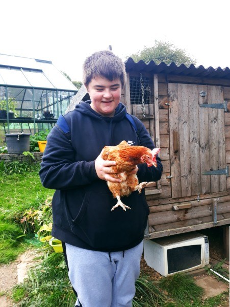 A young carer holds a chicken on a visit to a farm