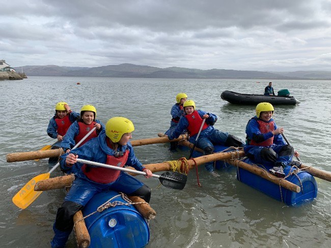 Six young people paddling on a homemade raft