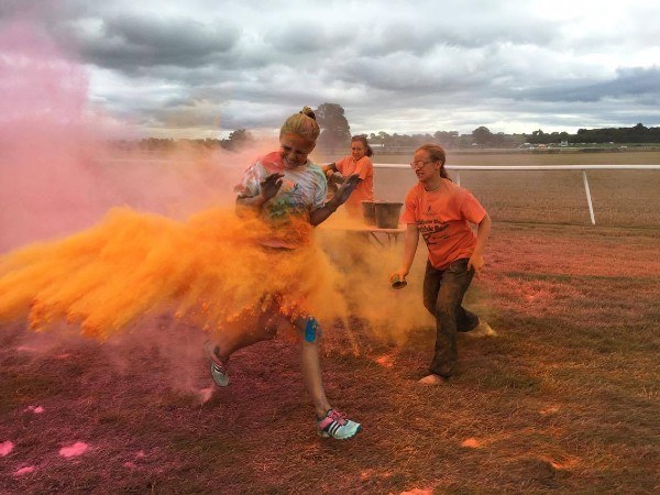 Young people at a Rainbow Run event covered in orange powder
