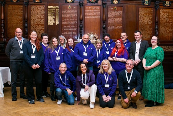 A team from the Thriving Survivors project smiling at the camera, some wearing the purple Thriving Survivors hoodies.