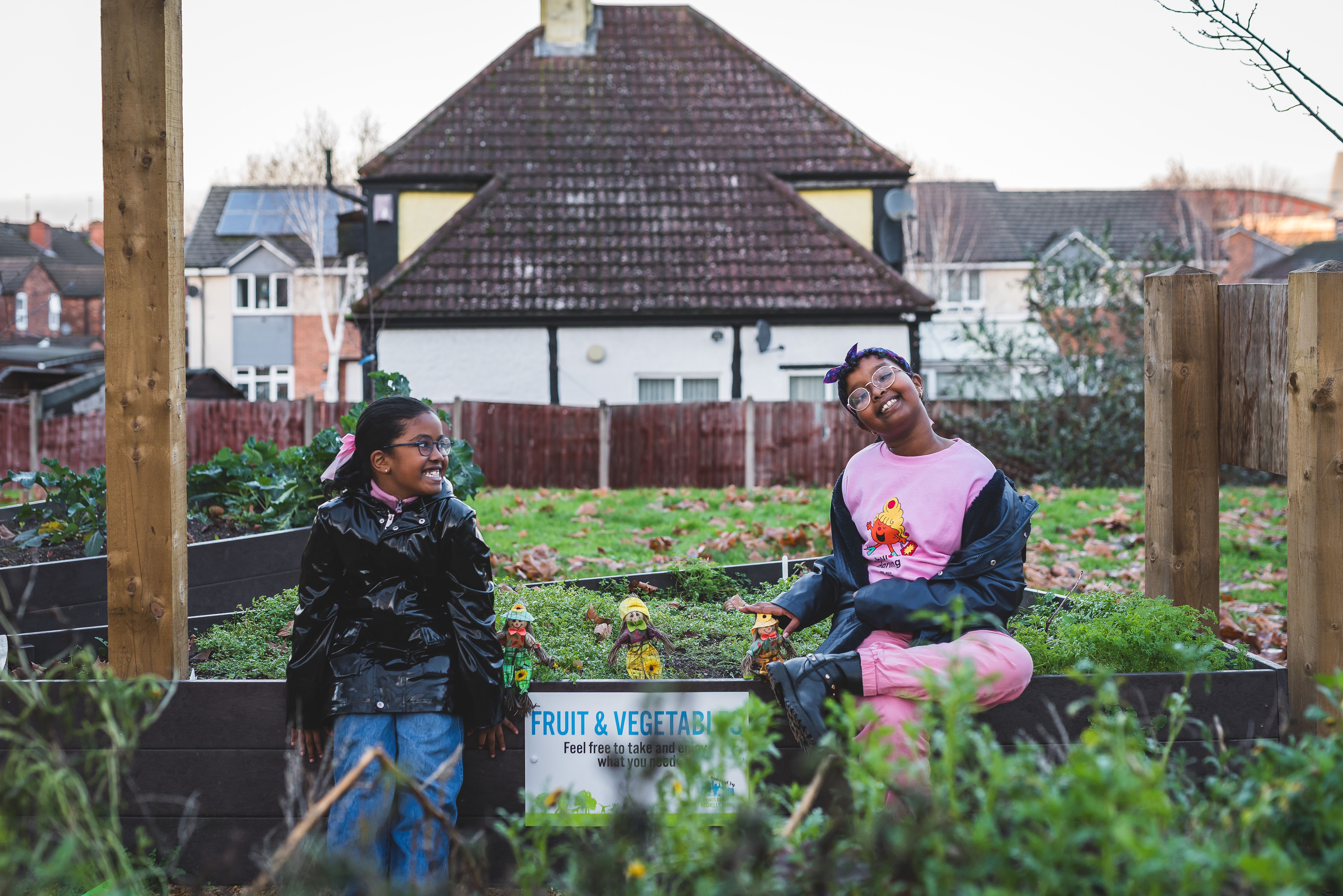 Two girls sitting in a flowerbed of a community garden