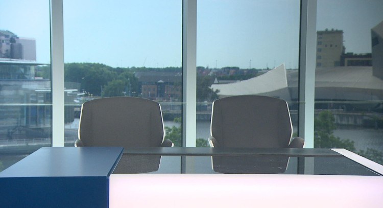 TV news desk with view over the water of Manchester’s Salford Quays, showing the Imperial War Museum