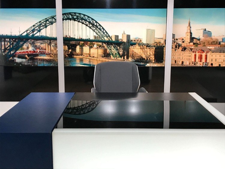 TV news desk with a view over the River Tyne behind, showing Newcastle and the Tyne Bridge