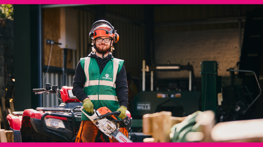 A man wearing high vis and safety helmet holding a chainsaw