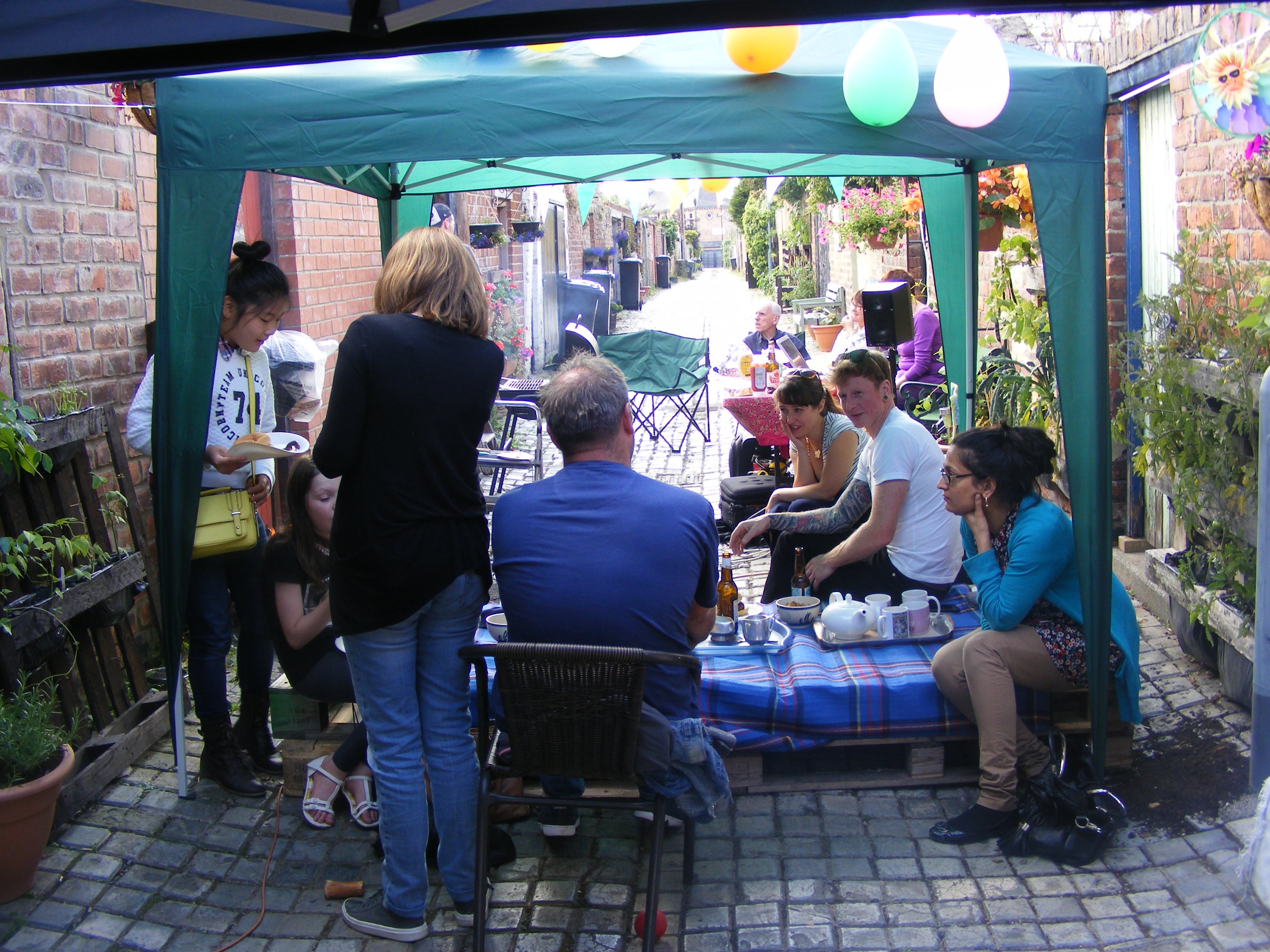 Members of Middlesbrough Environment City Alley Pals hosting an event in an alley behind terraced houses