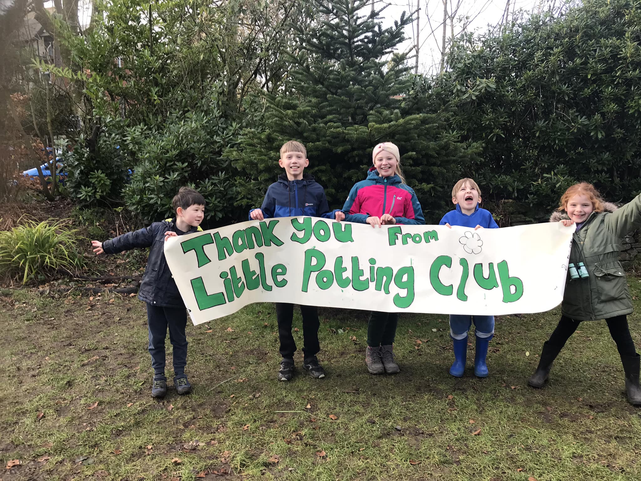 Plant yn dal baner sy'n dweud "diolch o'r Little Potting Club"