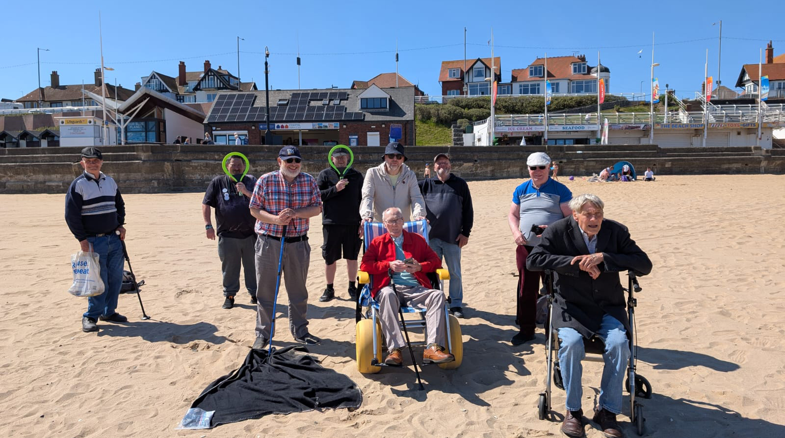 A group of smiling people from The Hinge Centre on the sand at Bridlington beach on a sunny day